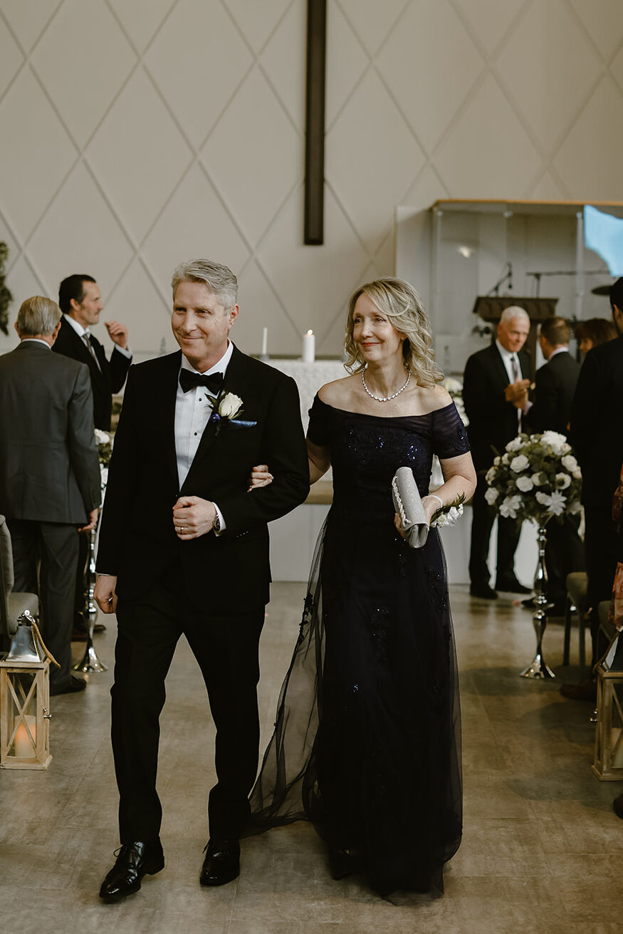 Brides parents walk down the aisle. 