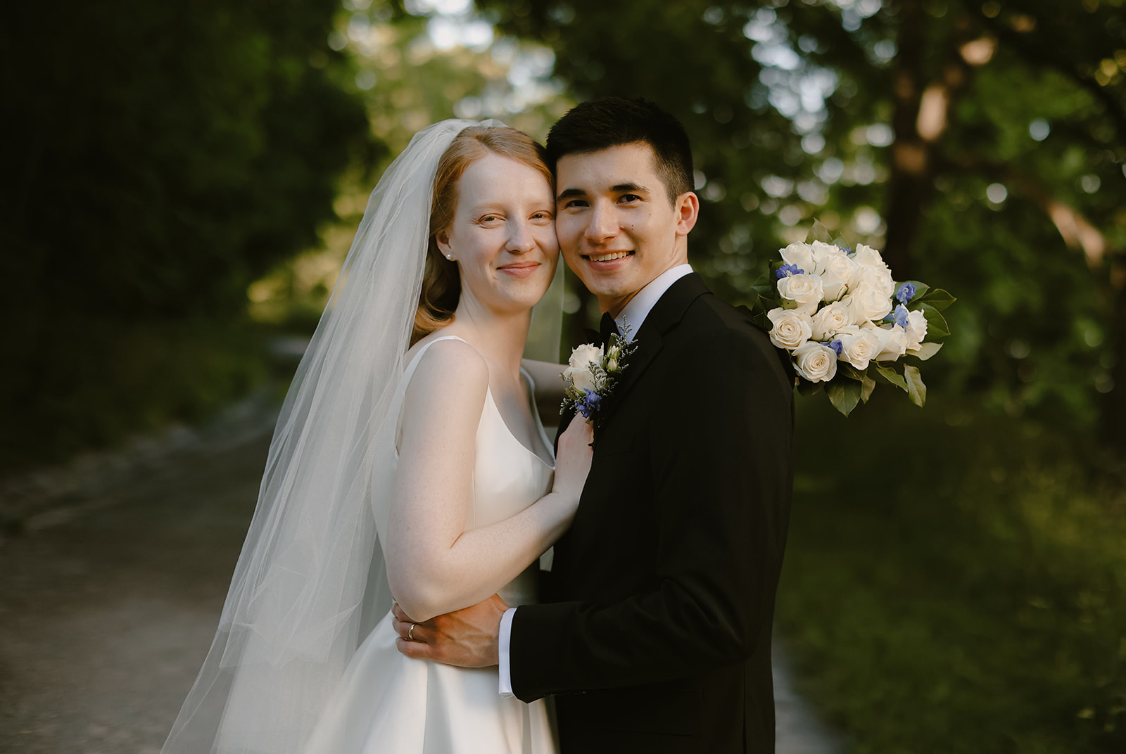 Bride and Groom smile at camera in close embrace. 