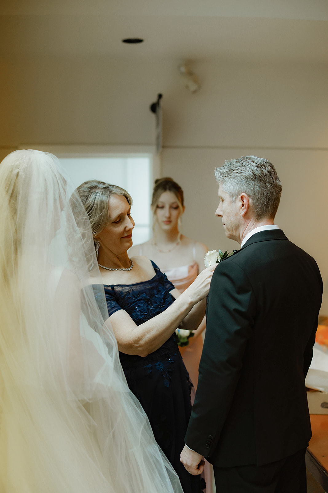 mother of the bride pins flower to lapel of brides father