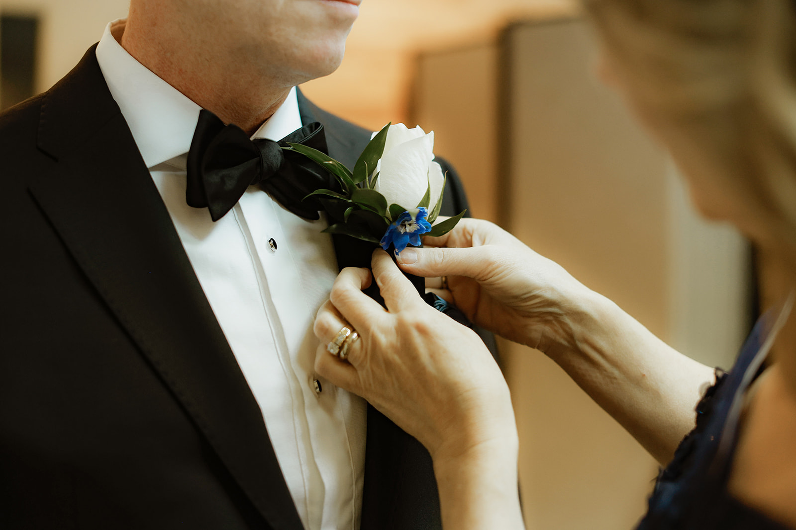 mother of the bride pins flower to lapel of brides father