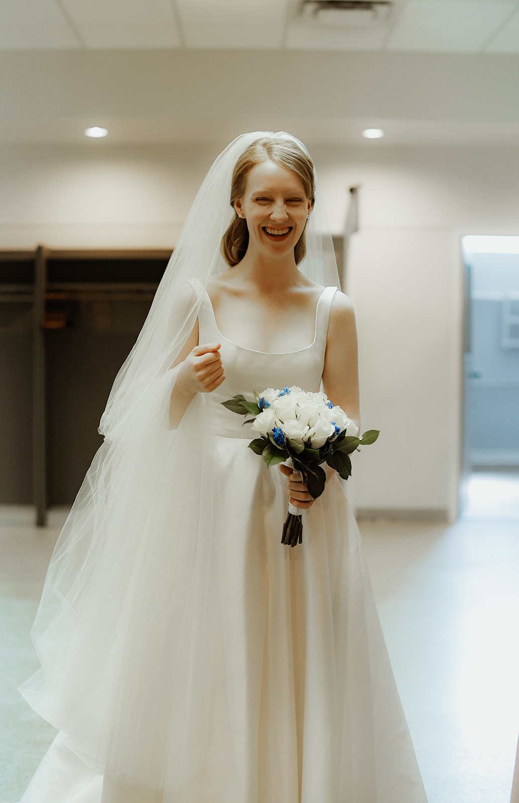 Bride smiles at camera while holing flowers