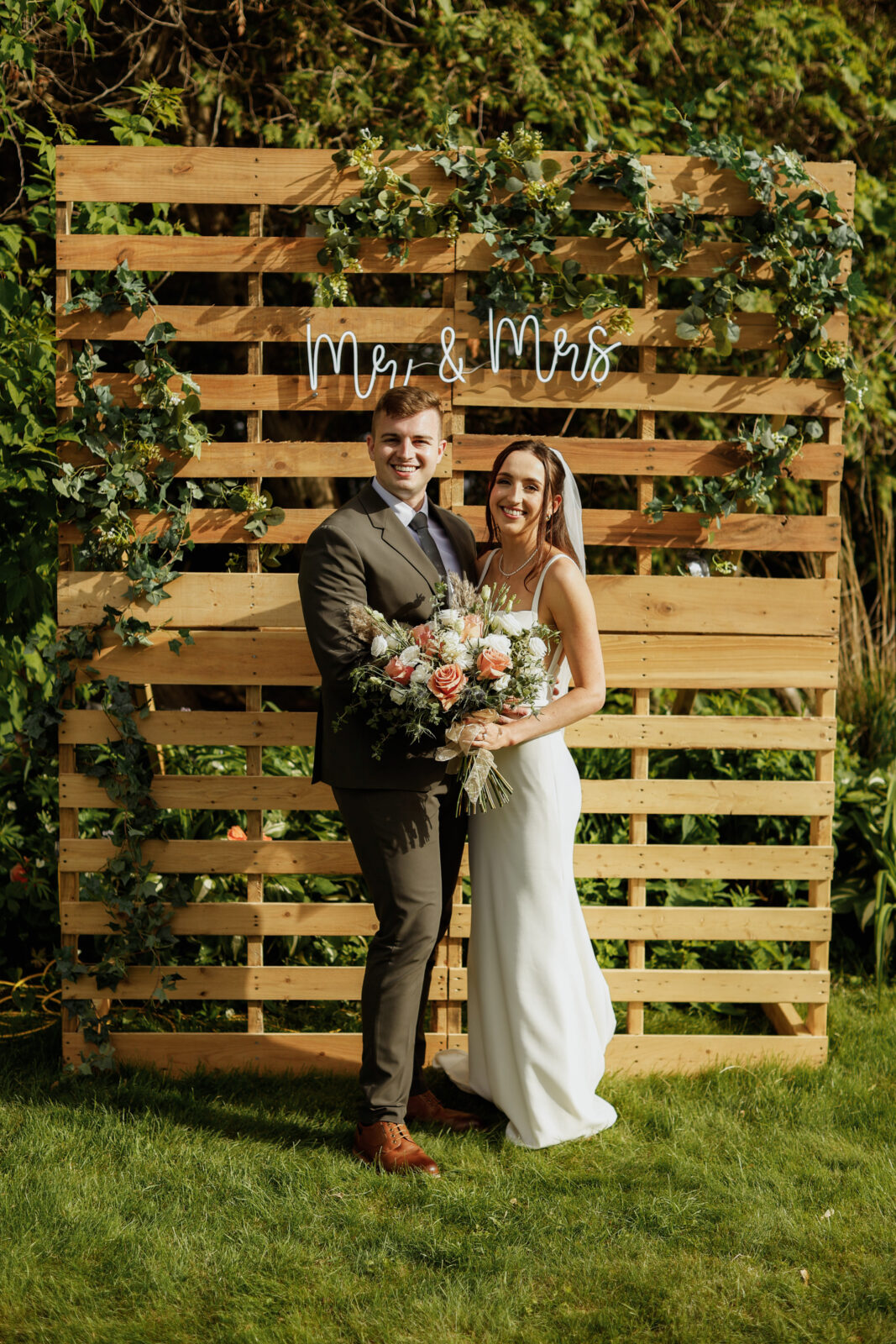 Bride and Groom smiling in front of Mr. & Mrs. sign