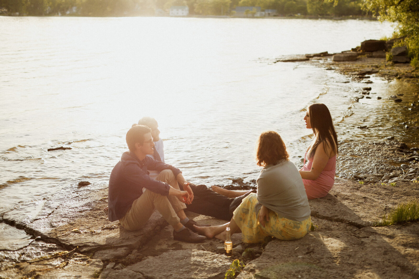 four guest sit on rocks talking as sun starts to set