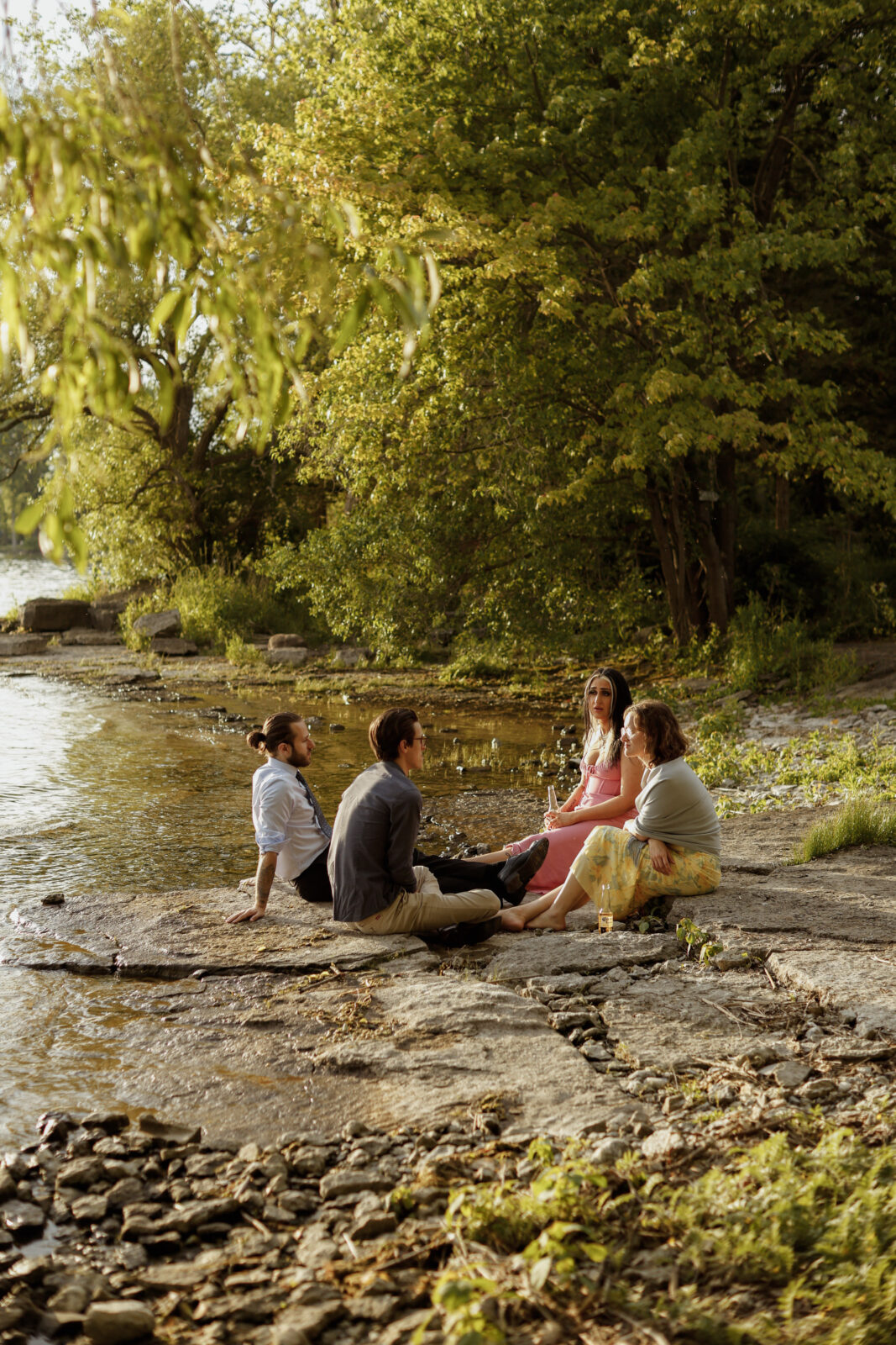 four guest sit on rocks talking as sun starts to set