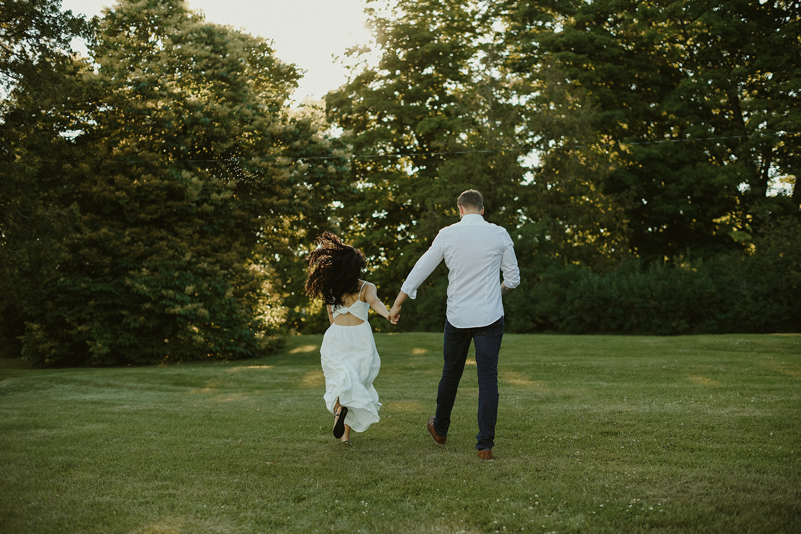 Couple holds hands and run away from camera. Kingston Ontario photography. 