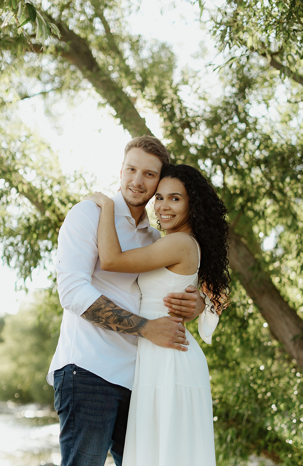 Man and woman hug under foliage. Engagement Photo