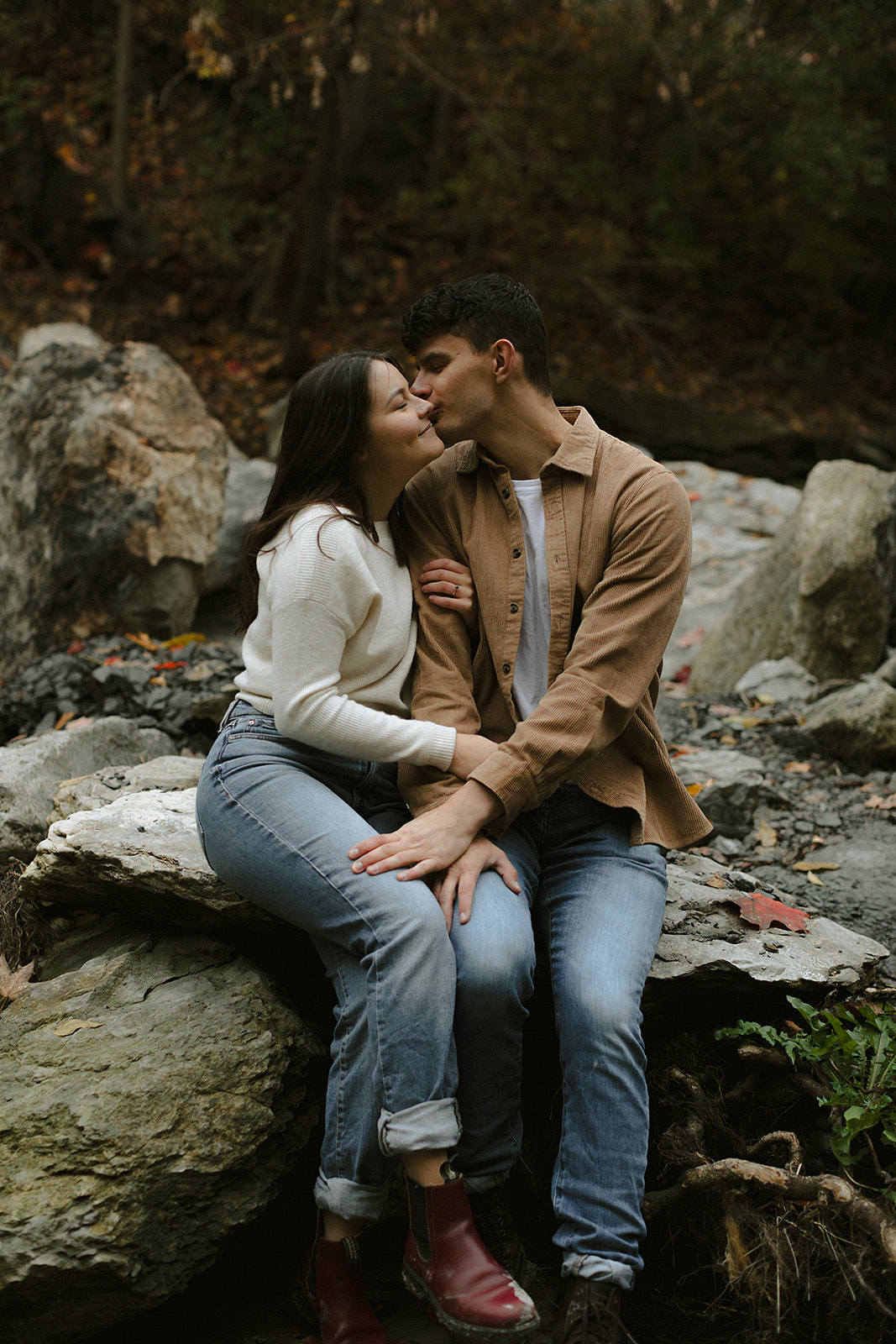 Couple sitting and kissing in scenic landscape - Engagement Photoshoot