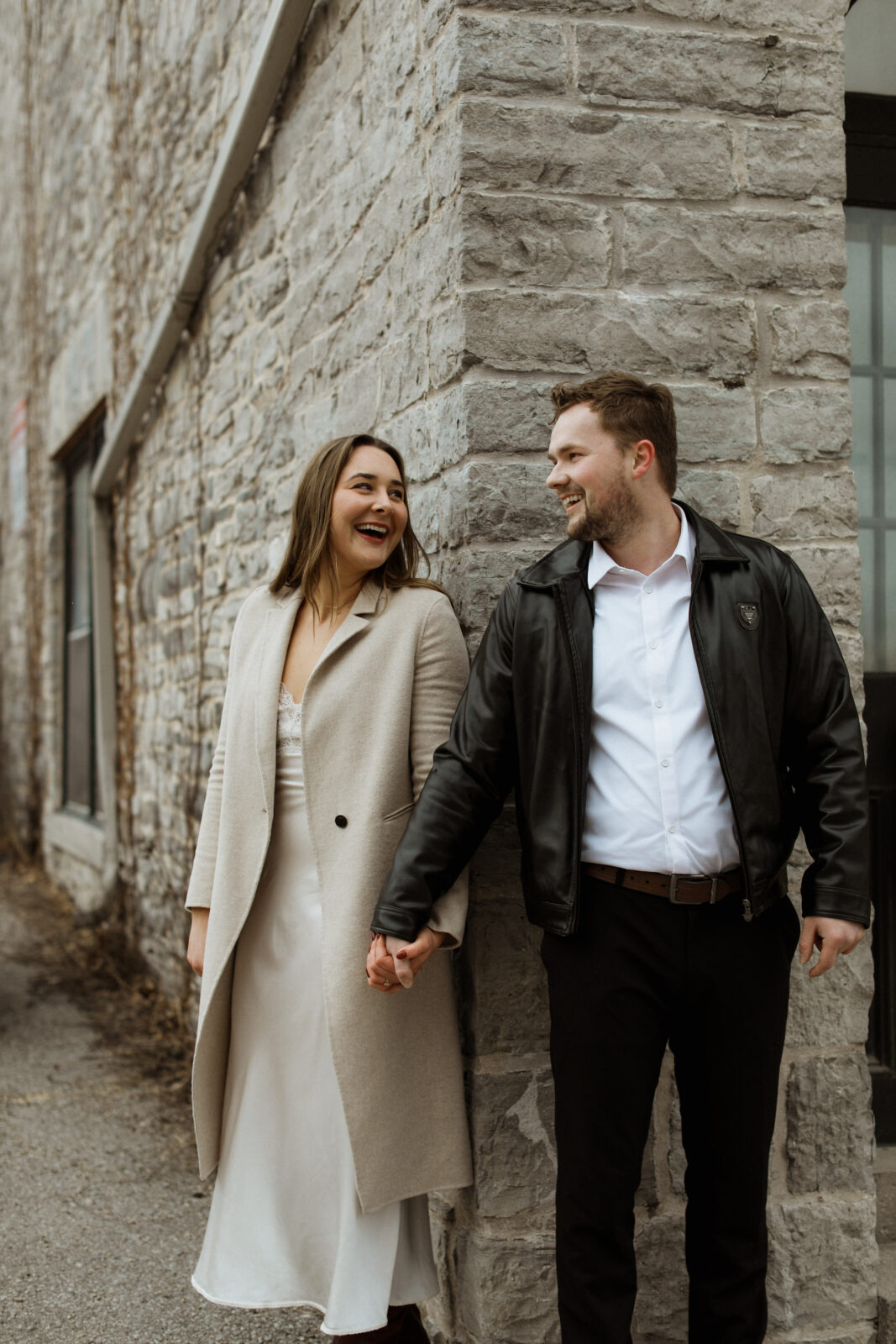 Couple holding hands. Background: Limestone wall