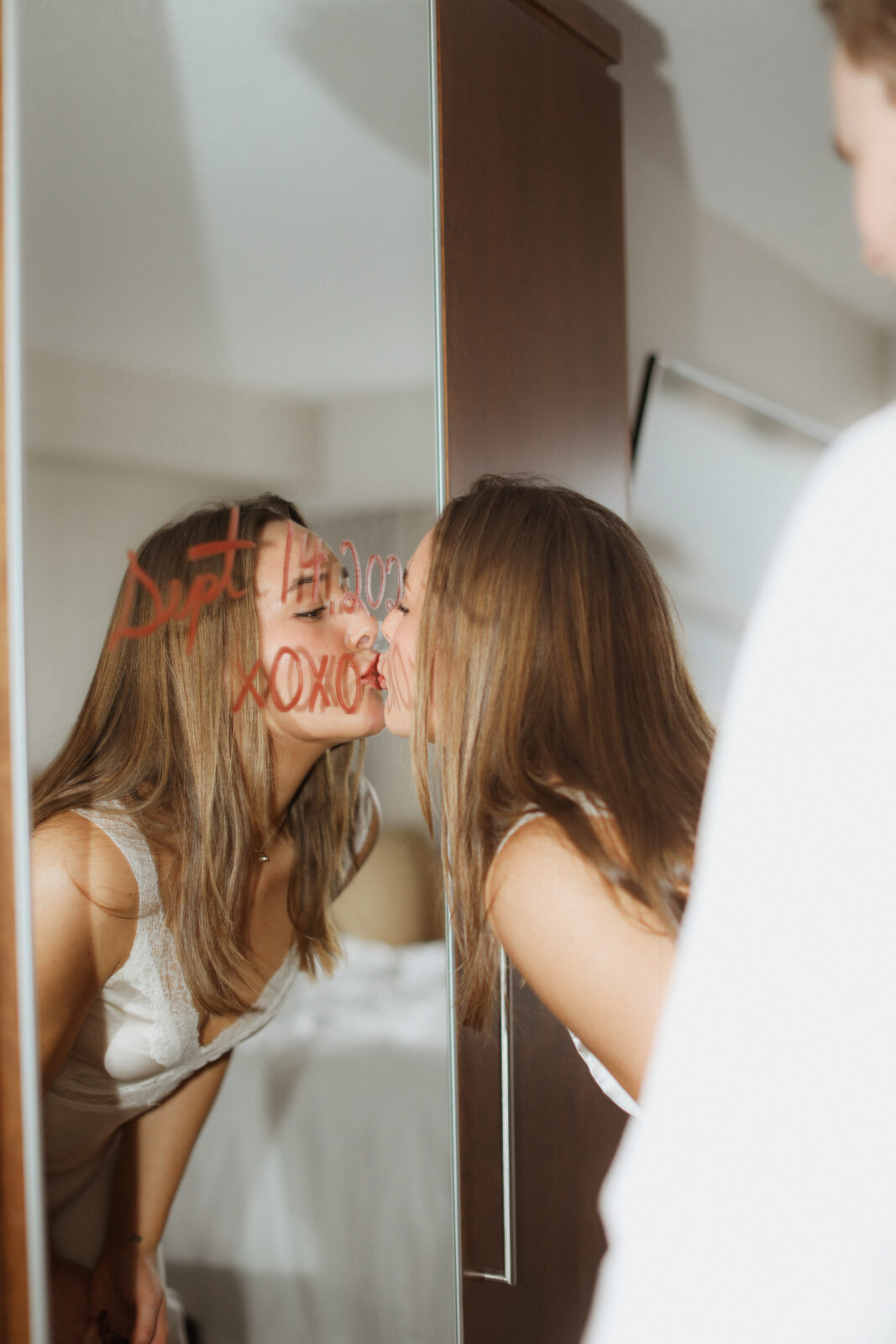 woman kisses mirror with wedding date written on it