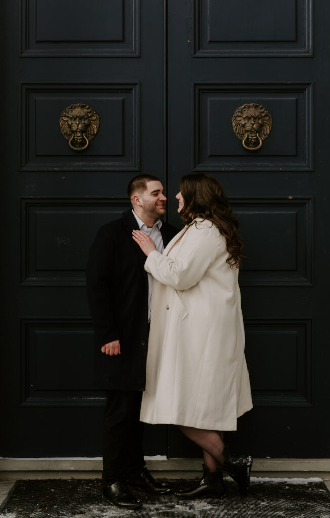 Couple stands in front of black doors