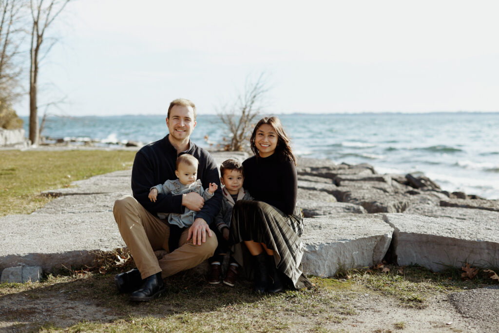Family sits on rock at shoreline - Kingston Ontario