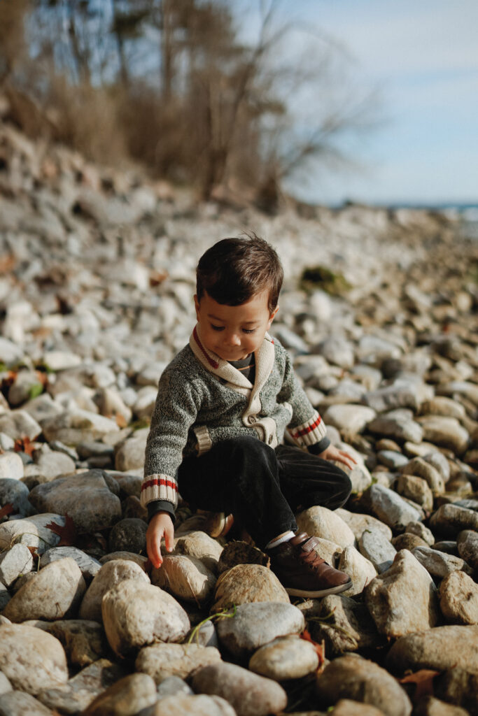 Child sits on rock cover beach