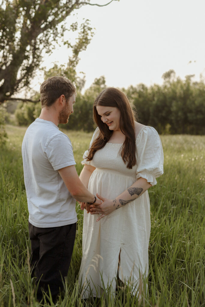 Couple holds hands in field 