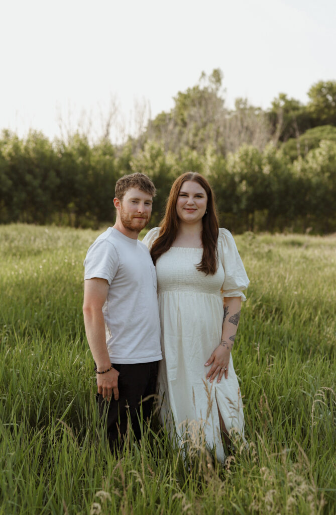 couple stands in green field 