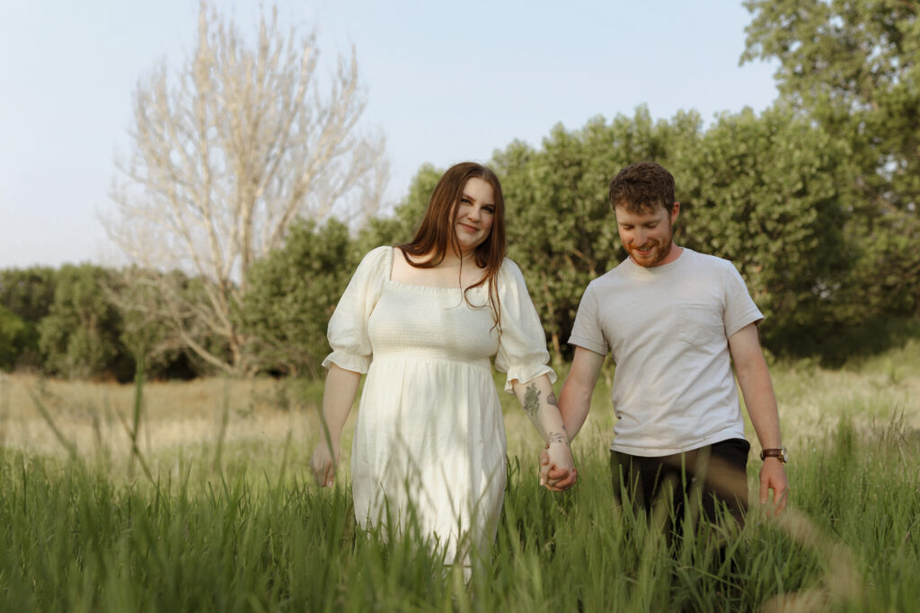 Couple holds hands and walks in field 