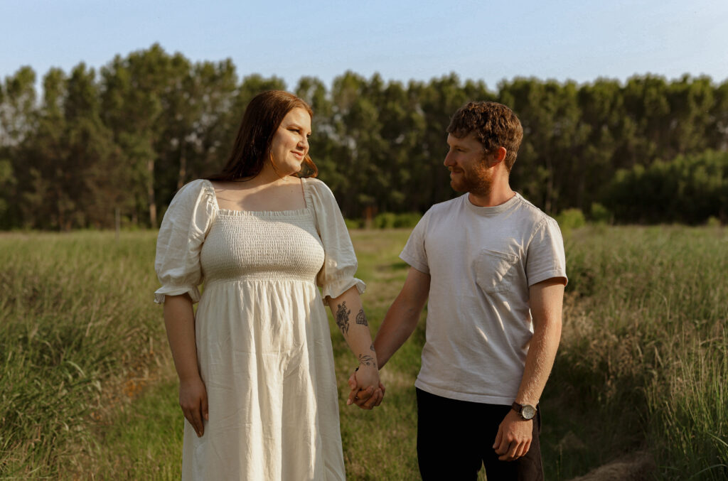 couple holds hand in field 