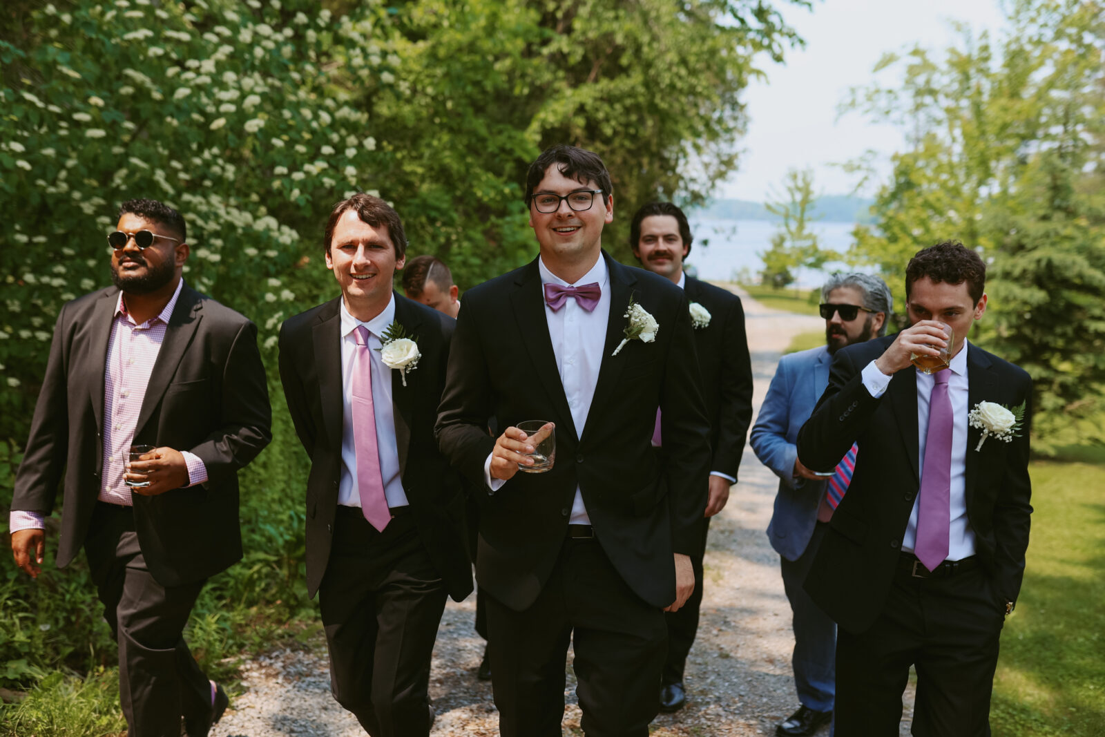 Groomsmen walk in a group with whiskey glasses