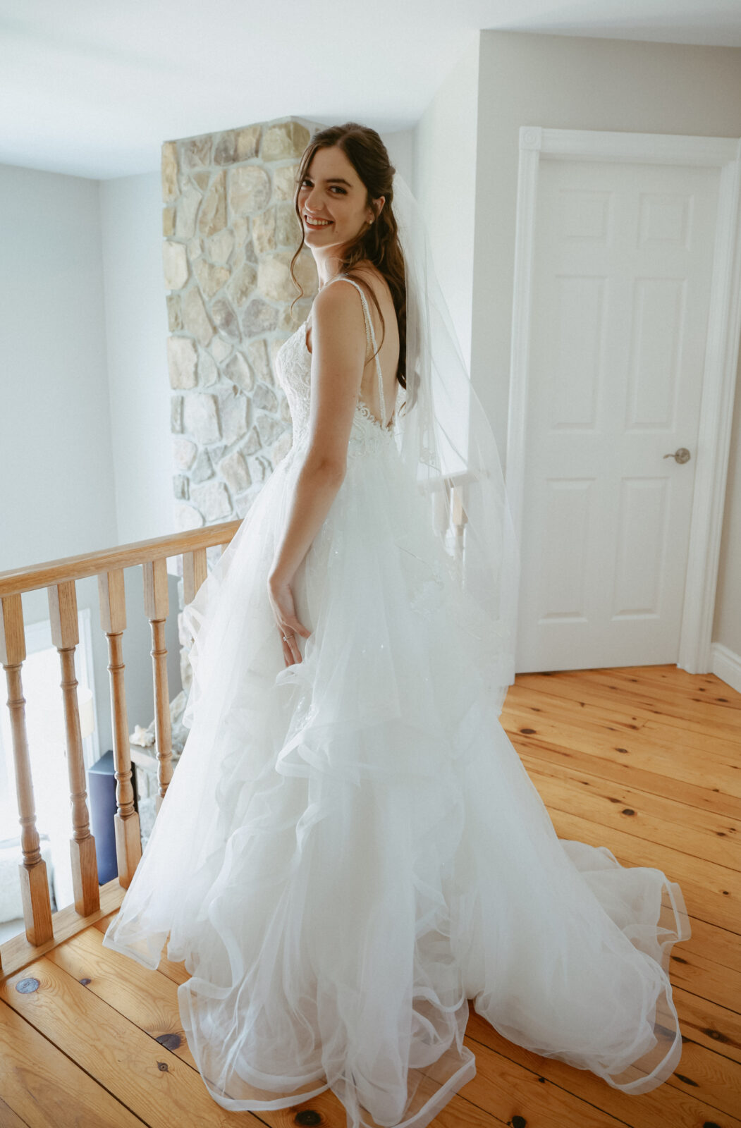 Bride stands in wedding dress looking back over her shoulder