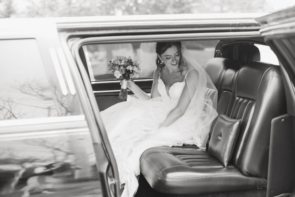 Black and white image of the bride getting in a limo.