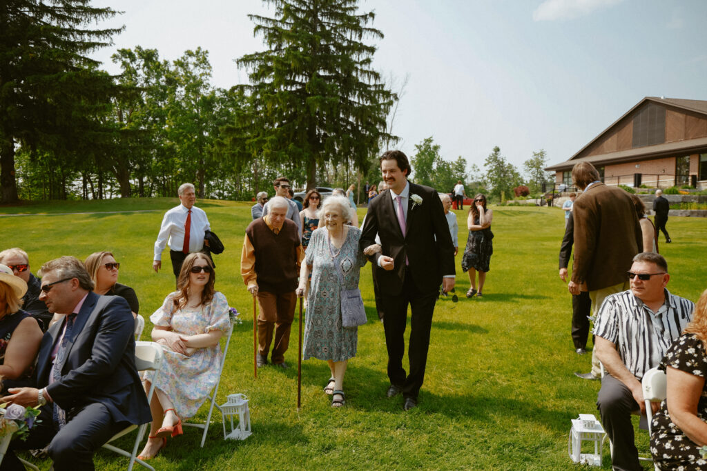 Groomsman walks senior wedding guest to their seat