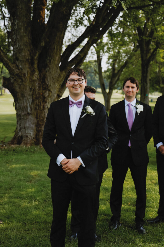 Groom smiles at camera while at alter waiting for the bride