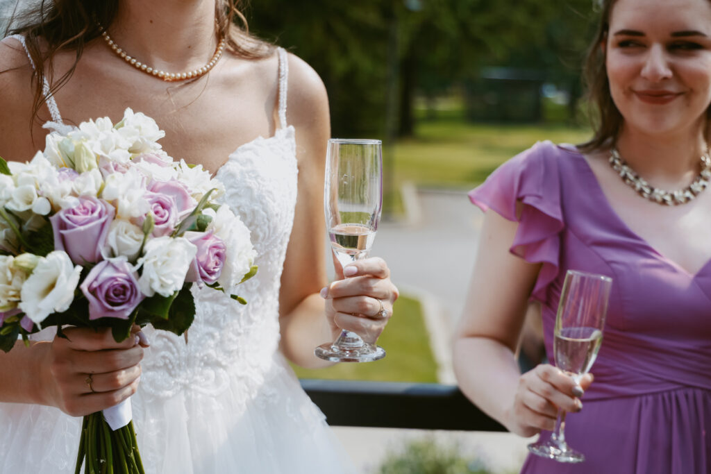 Bride with white and pink flowers holding glass of champaigh