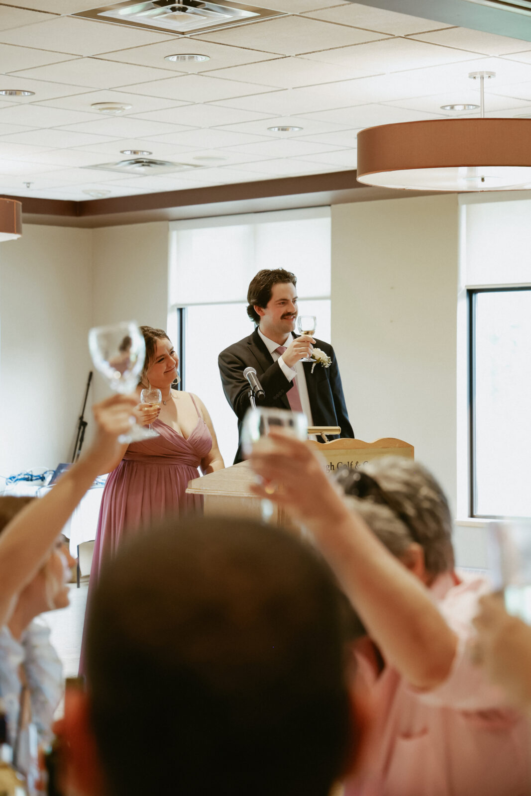 Bridesmaid and Groomsman hold up glasses for a toast