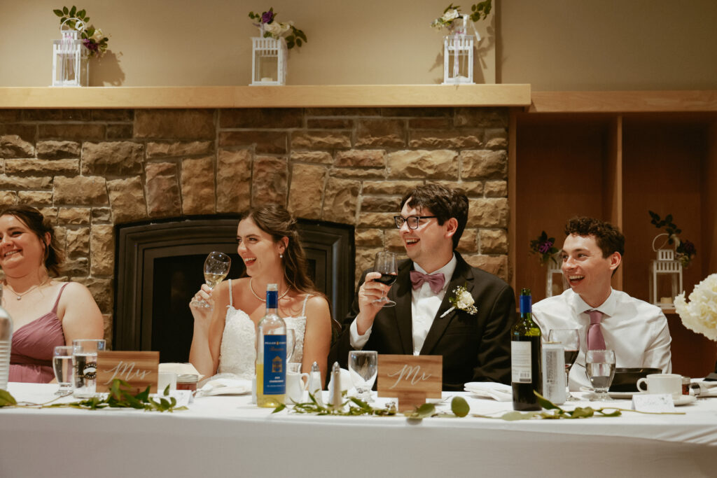Bride and groom laugh at speeches 