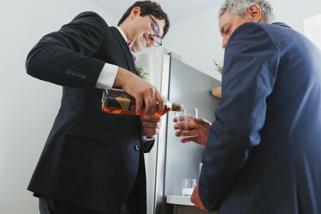 Groom pours whisky into glass