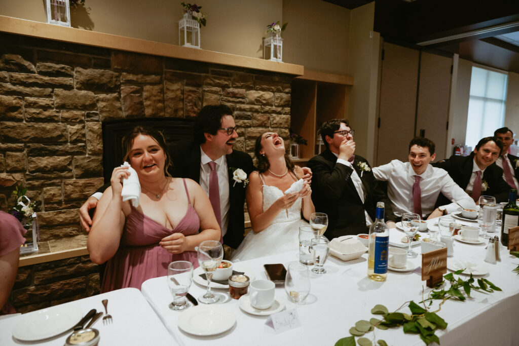 Bride and groom laugh at speeches 