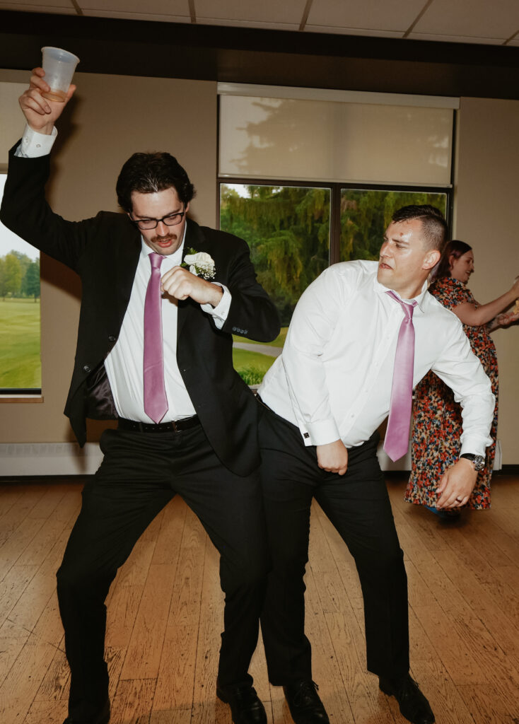 Men bump hips, dancing at wedding