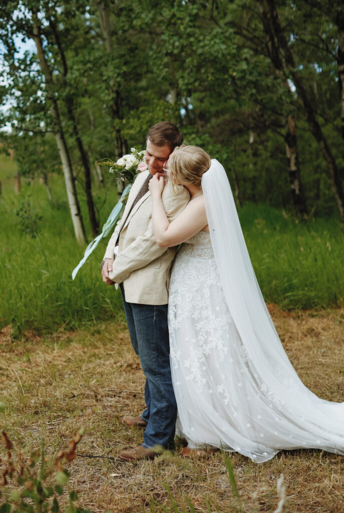 First look. Bride kisses grooms cheek from behind