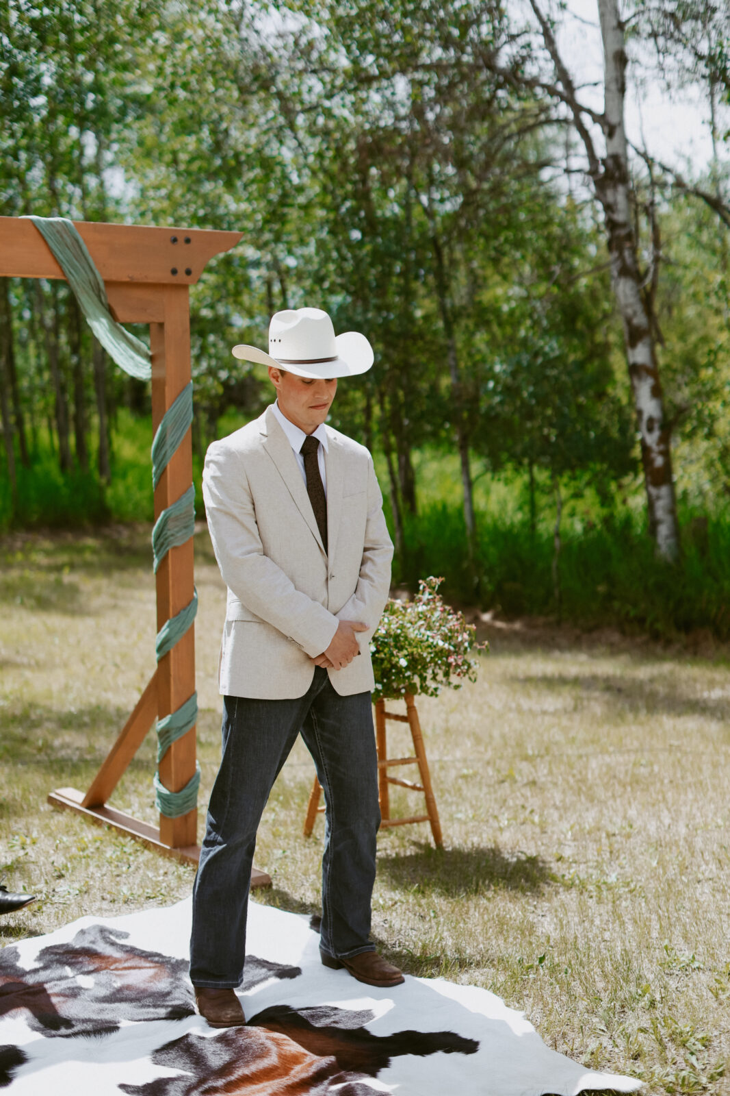 groom with cowboy hat stands at alter