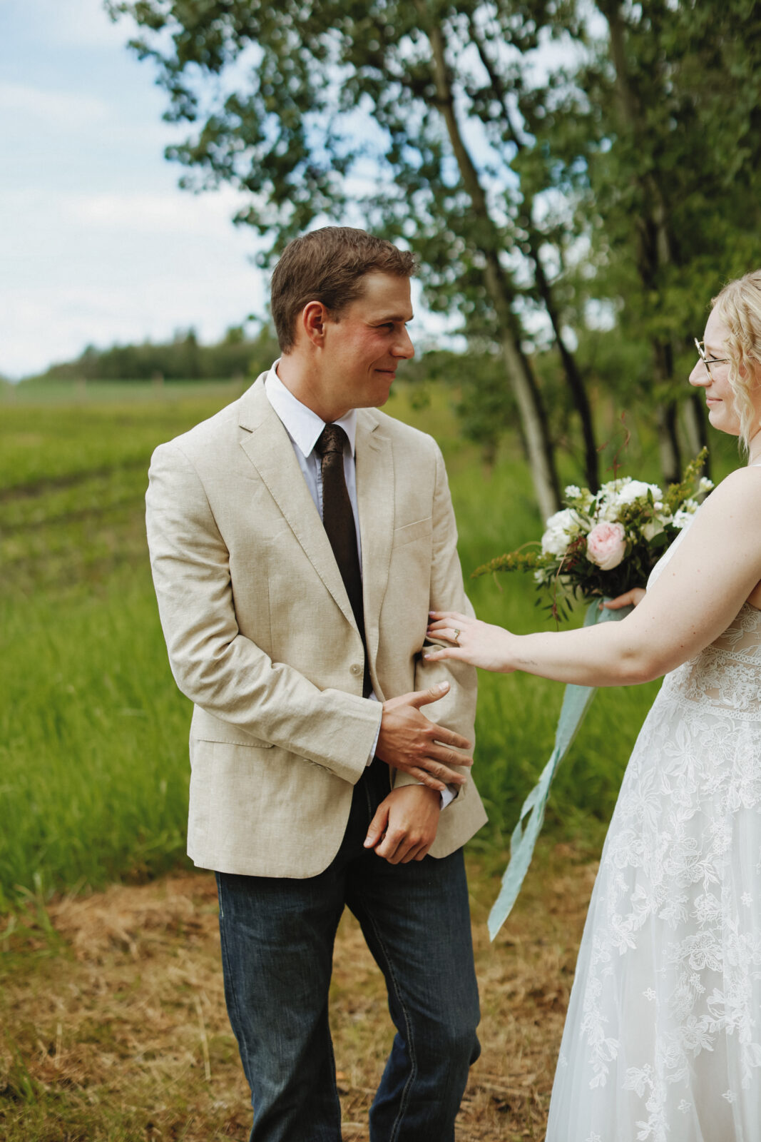 Groom turns to look at bride. Groom is smiling.
