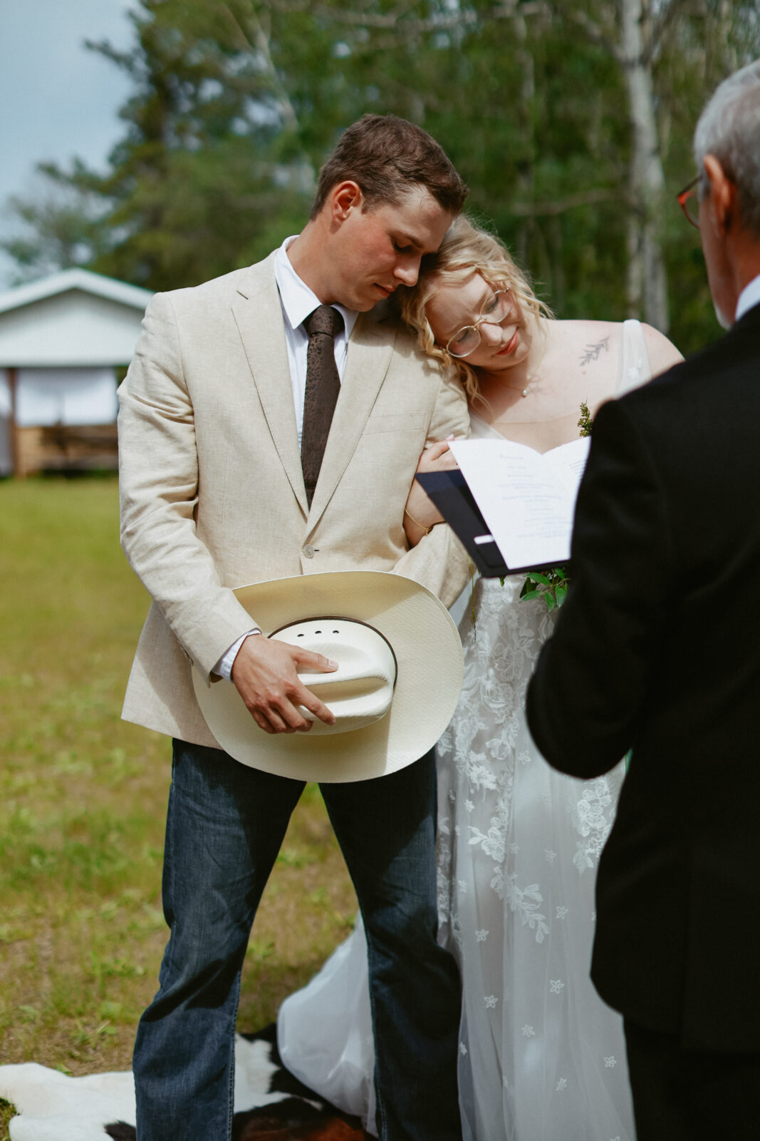 bridge and groom lean on each other while prayer is being read