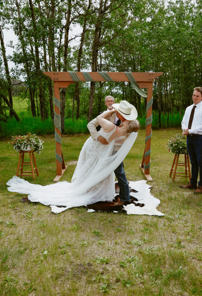 groom dips bride for a kiss at alter