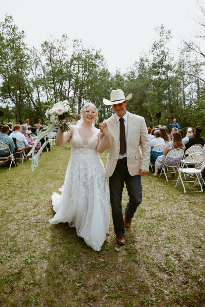 Bride and Groom walk down aisle hand in hand 