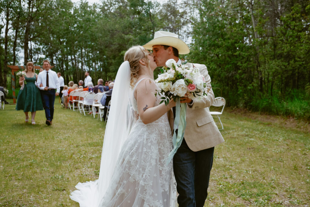 Bride and groom kiss while walking down alter