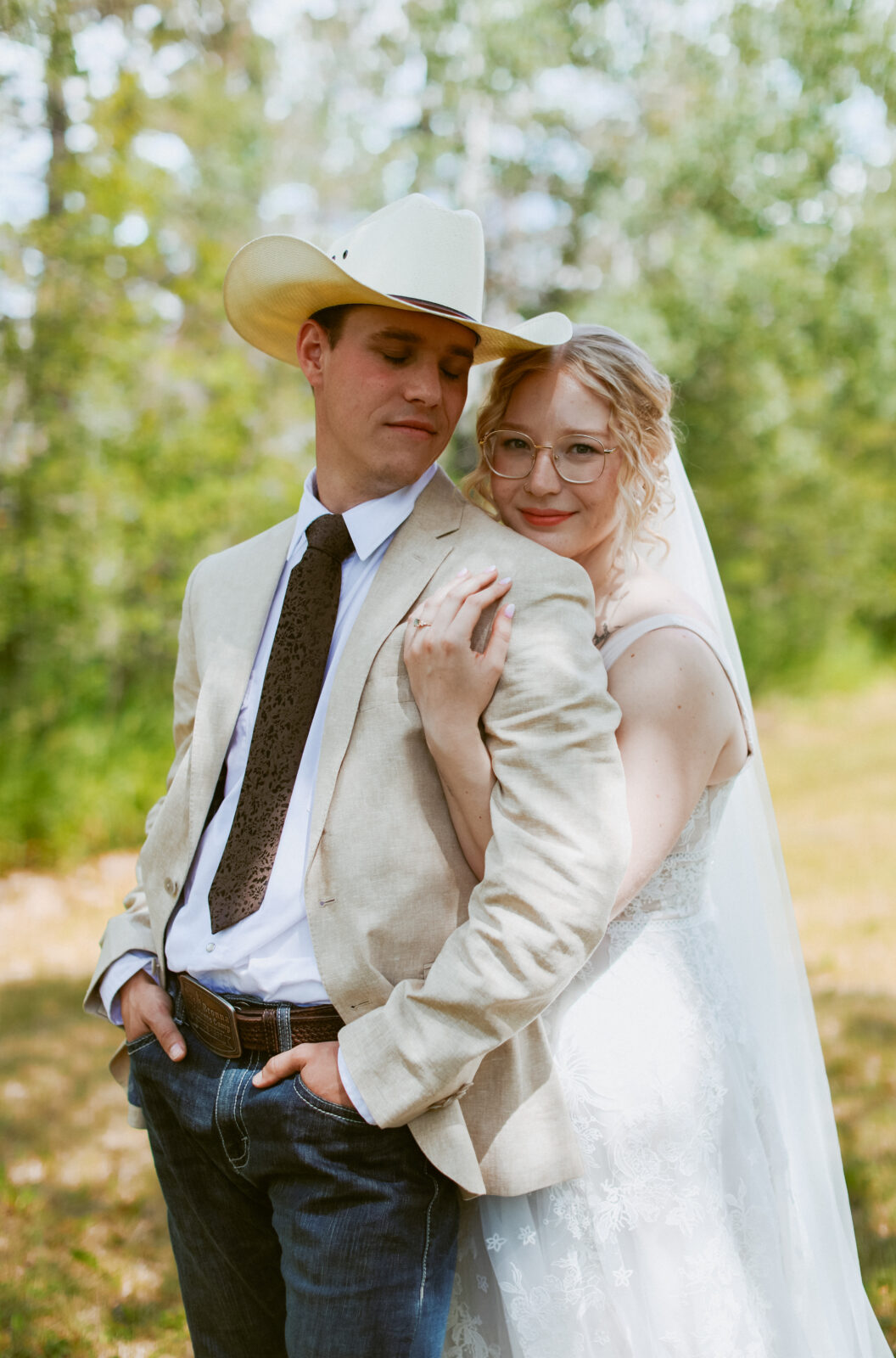 Bride hugs groom from behind.