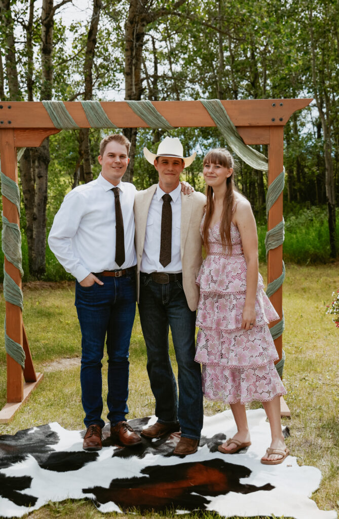 Groom stands at alter with sister and brother
