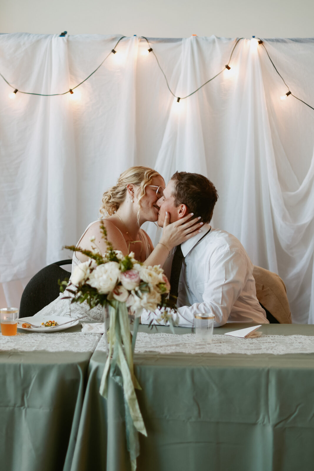 Bride and groom kiss at head table.