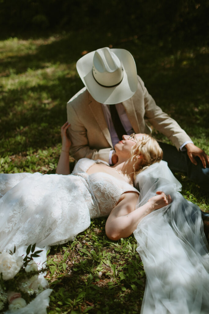 Bride lays down with head in grooms lap.