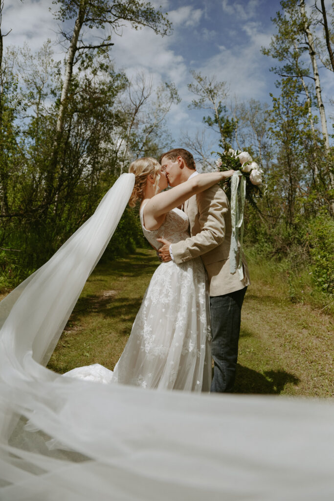 Bride and Groom kiss with a long veil in the forefront of the photo