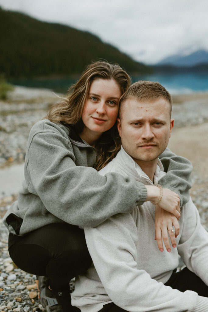 Couple hugs on a rock shoreline in Alberta.