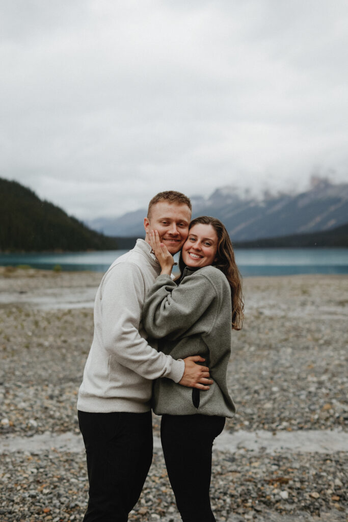 Couple hugs on a rock shoreline in Alberta.