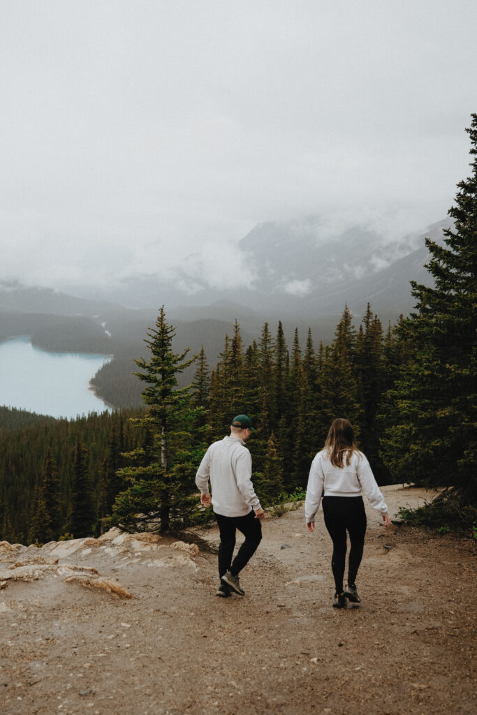 Couple walks down mountain with trees in the background