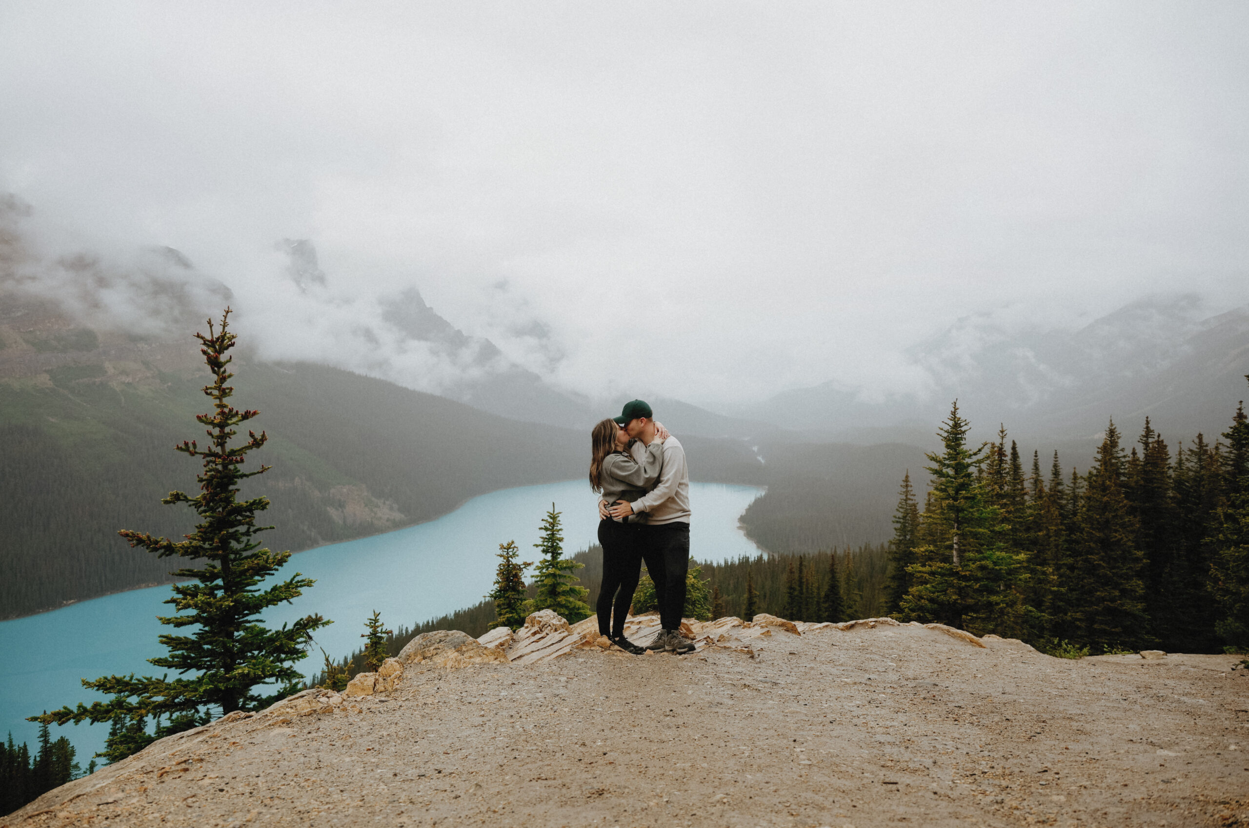 couple kisses atop a mountain