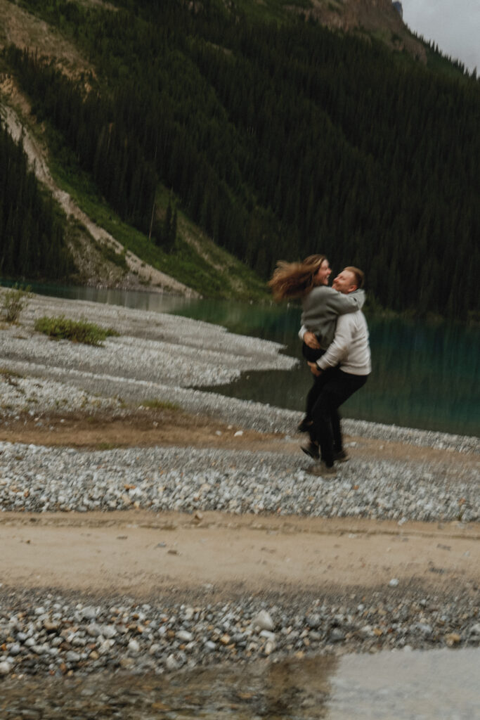 Man swings woman on a rock beach in Alberta.