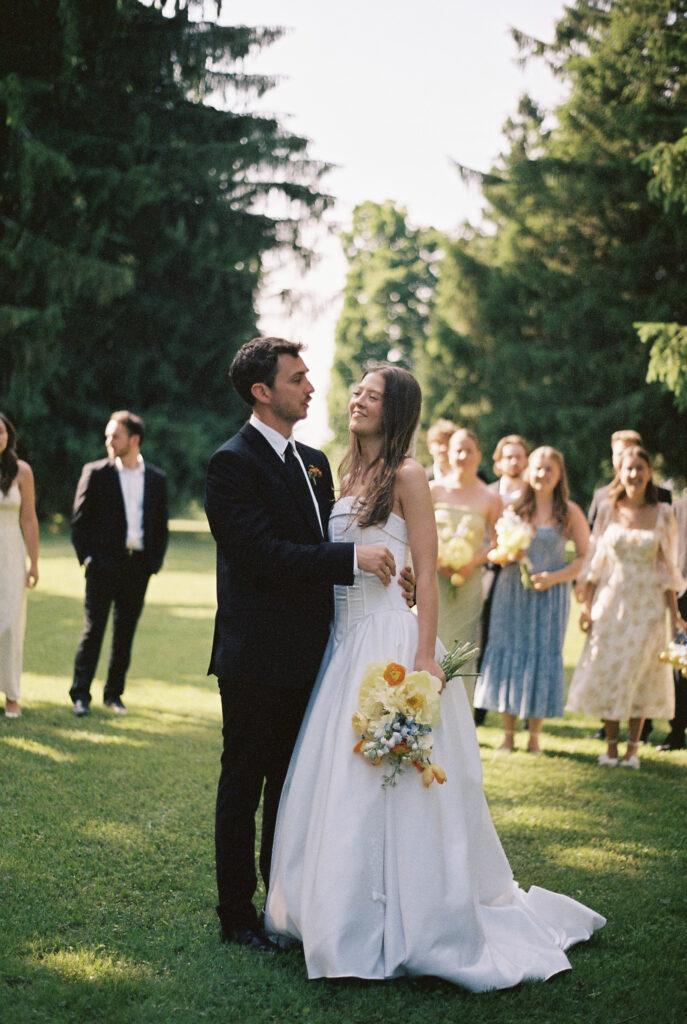 Bride and Groom hold each other while wedding party is in the background. 
