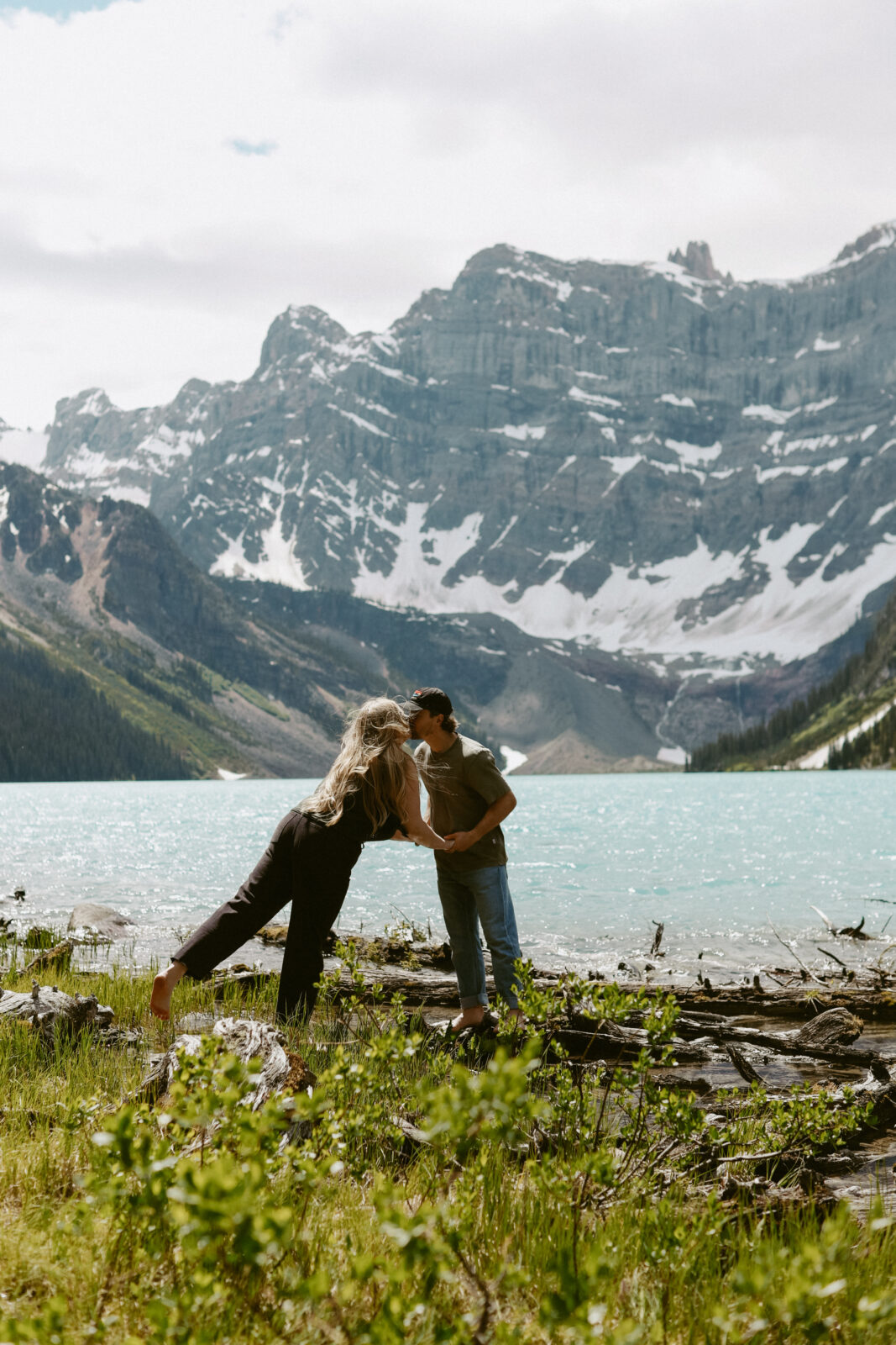 Couple kisses with mountains and lake in background